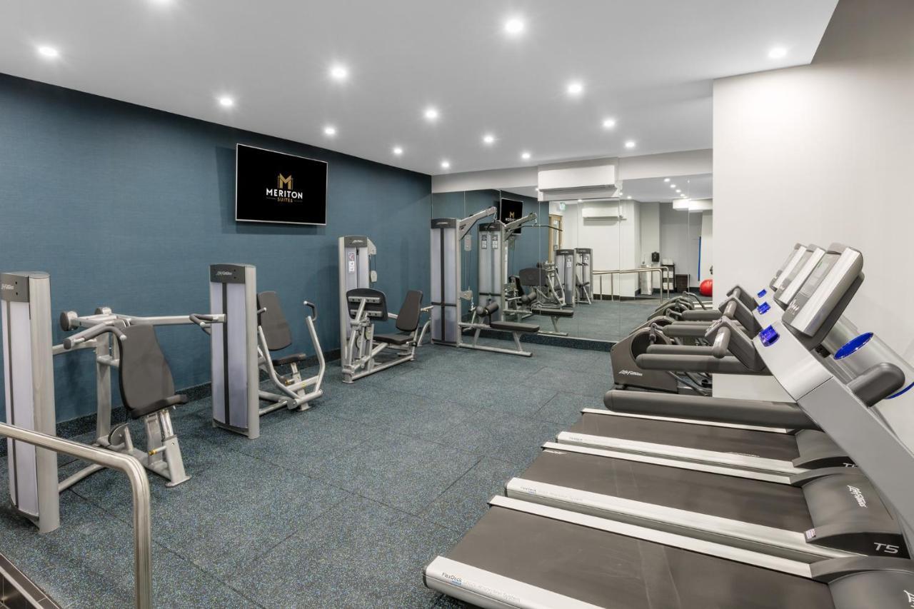 Meriton Suites Sussex Street, Sydney Ngoại thất bức ảnh The photo shows a modern gym interior. The space features several pieces of exercise equipment, including weight machines and stationary bikes. The walls are painted a calming color, and the flooring is carpeted. There are also mirrors on the walls, 