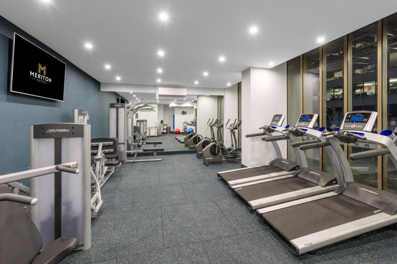 Meriton Suites Sussex Street, Sydney Ngoại thất bức ảnh The photo shows a modern gym space. It features various exercise equipment, including several treadmills and elliptical machines positioned along one side. On the other side, there are weight machines and additional fitness equipment. The gym has a c