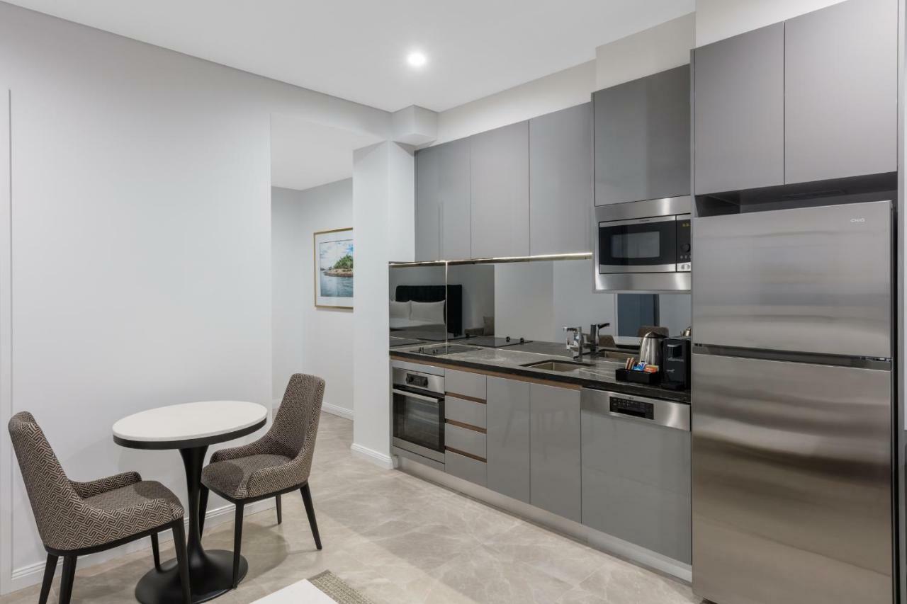 Meriton Suites Sussex Street, Sydney Ngoại thất bức ảnh The photo shows a modern kitchen area that features a sleek design. The cabinetry and appliances are in shades of gray, giving it a contemporary look. There is a stainless steel refrigerator, microwave, and oven, along with a sink and cooking area. 
